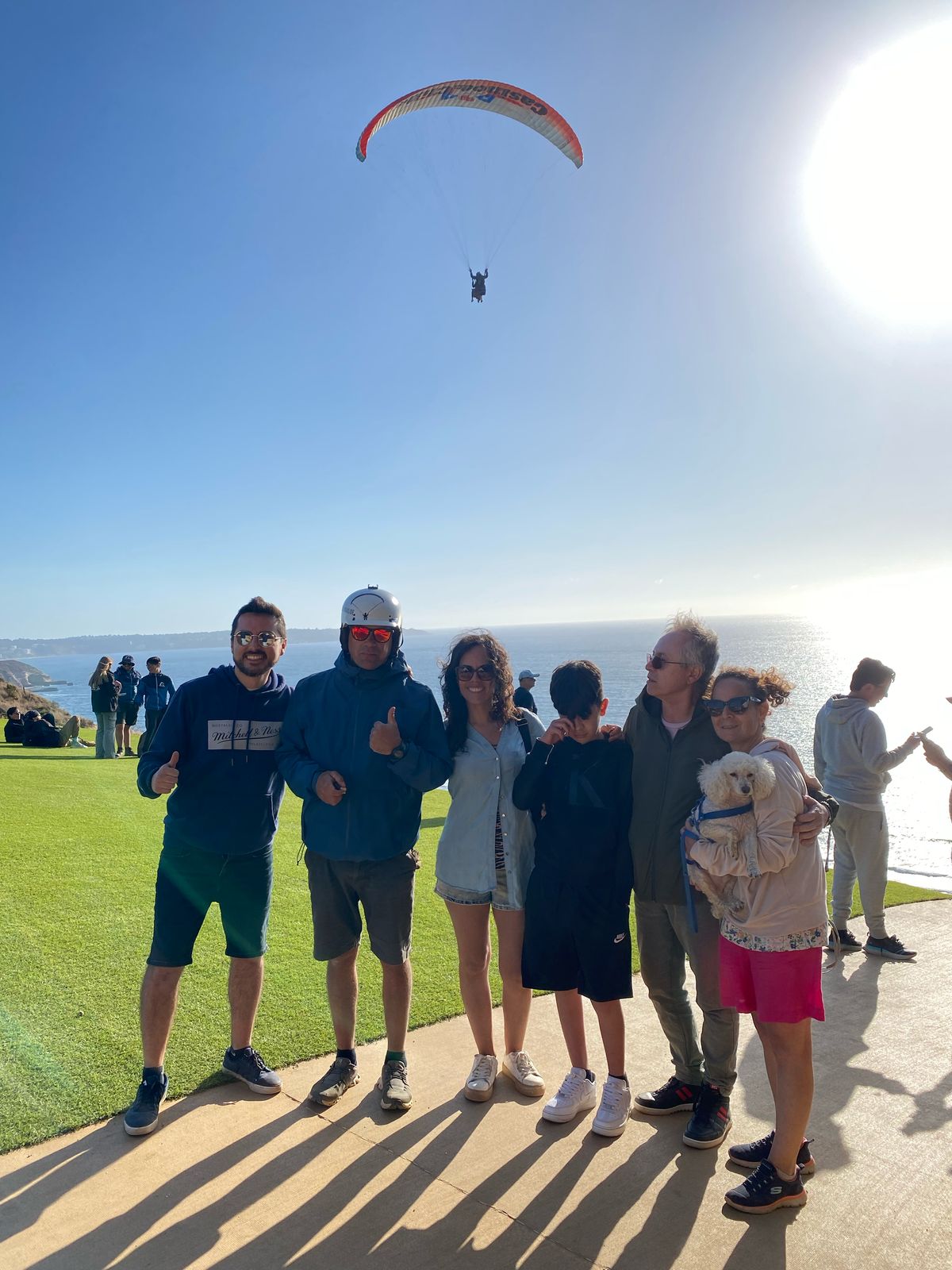 Familia y amigos disfrutando de un vuelo en parapente junto al mar